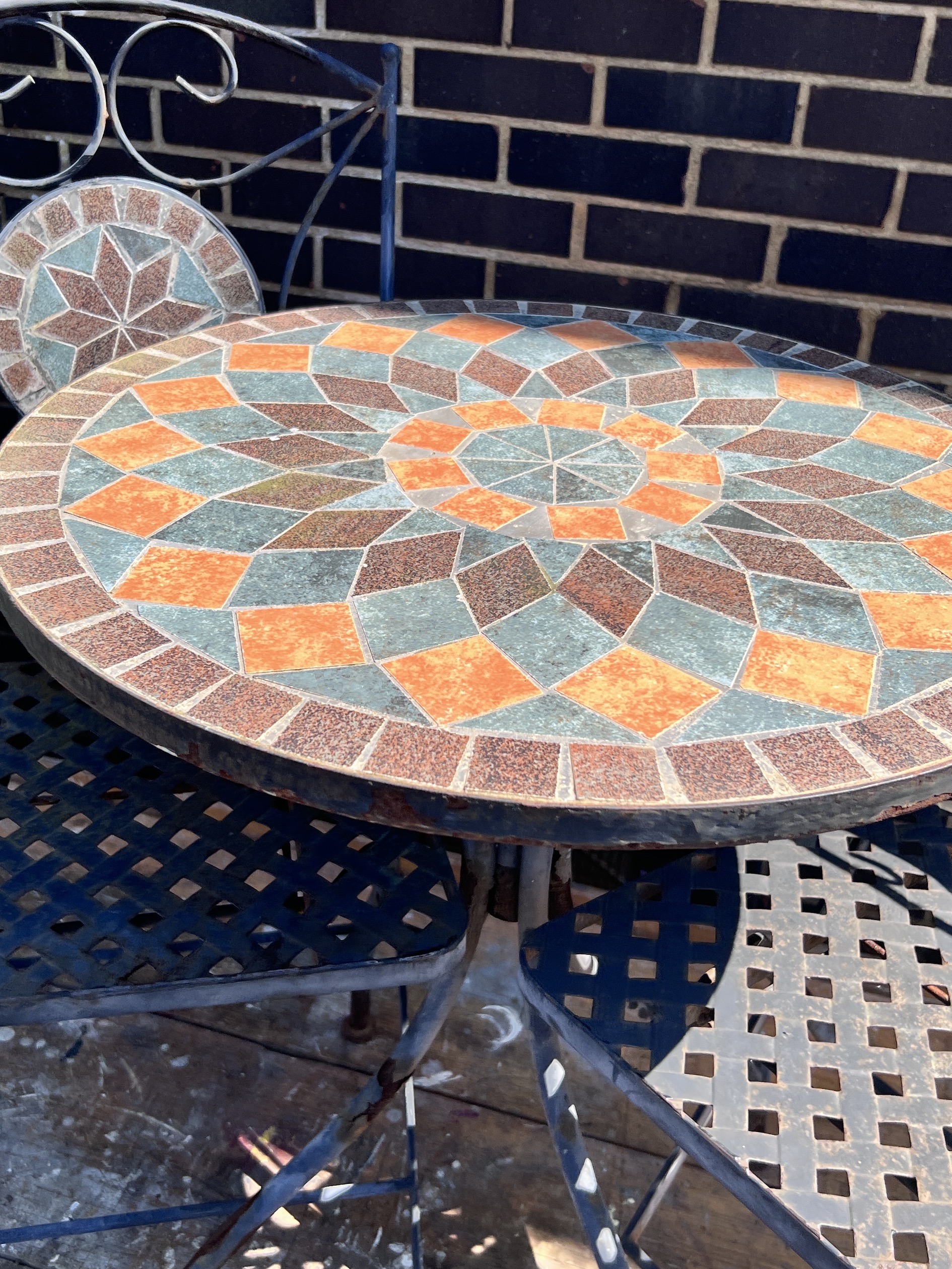 A circular mosaic topped garden table, diameter 60cm, height 73cm, and a pair of matching folding chairs